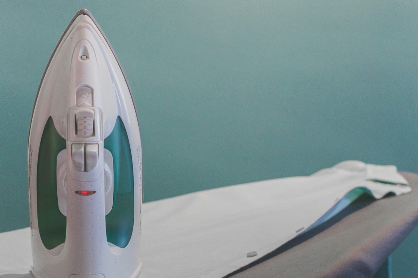 Hauswirtschaftliche Leistungen Dampfstation und glattes, gebügeltes Hemd auf einem Bügelbrett.