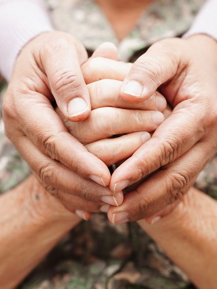 Schützende Hände Zwei Hände, die zwei ältere Hände umschließen. Das Bild symbolisiert Unterstützung und Fürsorge.